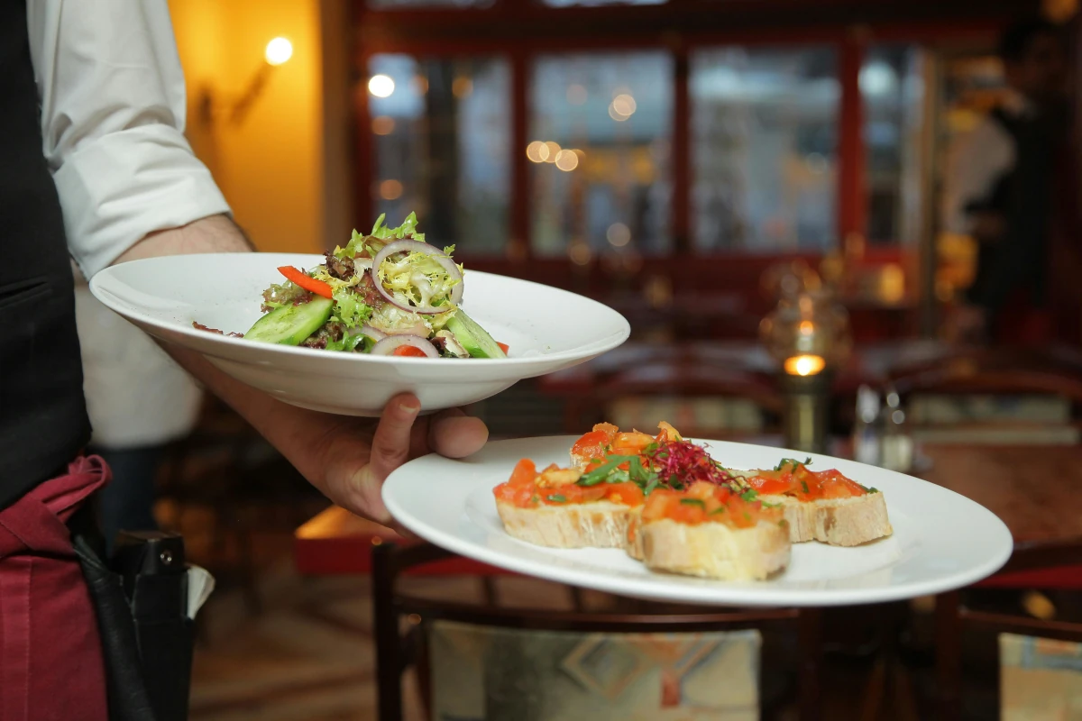 Kelner podaje świeżą sałatkę i grzanki z pomidorami w restauracji
